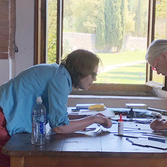 Photograph of Rebecca Goodale working on a book project alongside a colleague at a work table in front of a window.